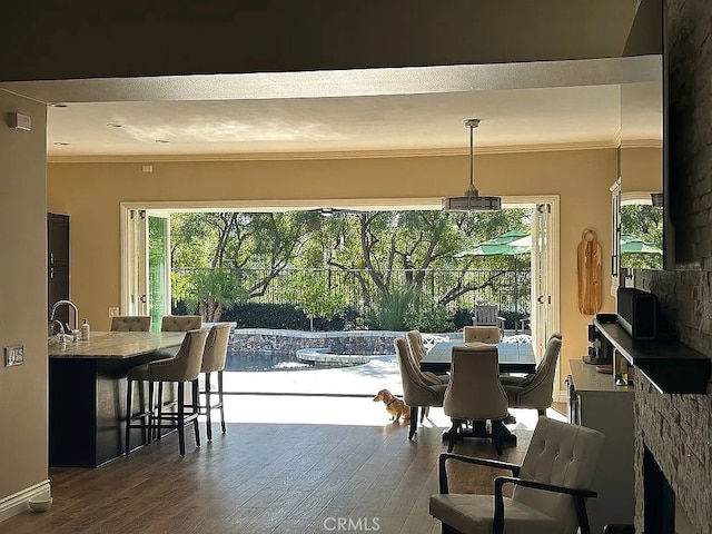 dining area with a healthy amount of sunlight, crown molding, wood-type flooring, and sink