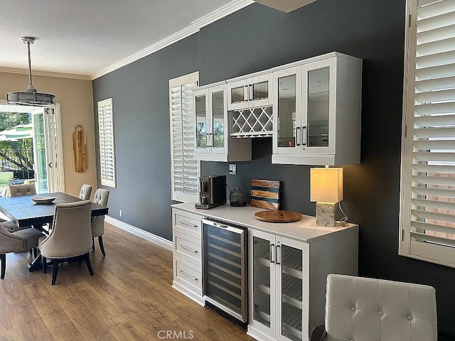 bar with hardwood / wood-style floors, white cabinets, wine cooler, ornamental molding, and decorative light fixtures