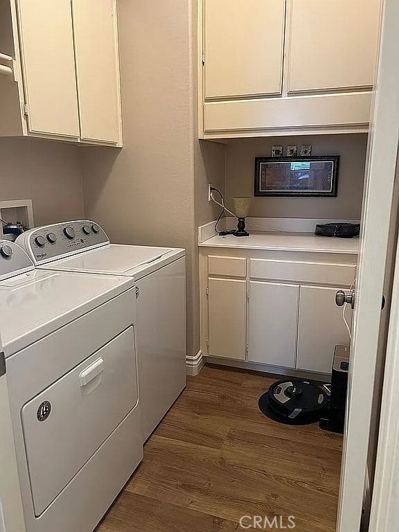 clothes washing area with dark wood-type flooring, cabinets, and independent washer and dryer