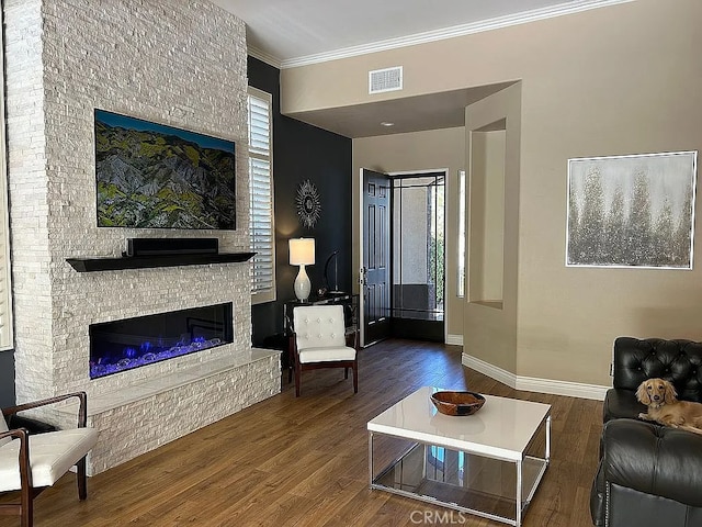 living room with a stone fireplace, crown molding, and dark wood-type flooring