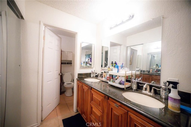 bathroom featuring toilet, vanity, a textured ceiling, and tile patterned floors