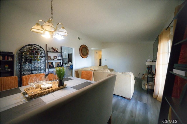 dining space with dark hardwood / wood-style floors and a notable chandelier