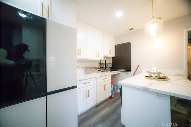 kitchen featuring white cabinets, white refrigerator, dark hardwood / wood-style floors, light stone countertops, and decorative light fixtures