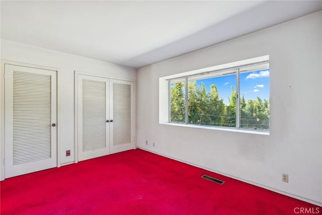 unfurnished bedroom featuring carpet flooring and two closets