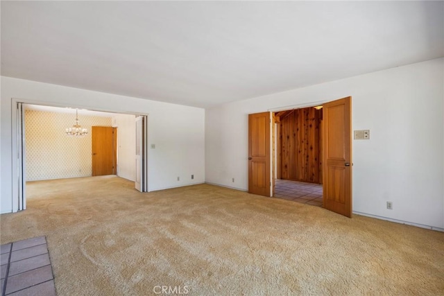 empty room with light carpet and a chandelier