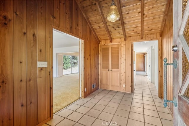 interior space with lofted ceiling with beams, wooden walls, light tile patterned floors, and wood ceiling