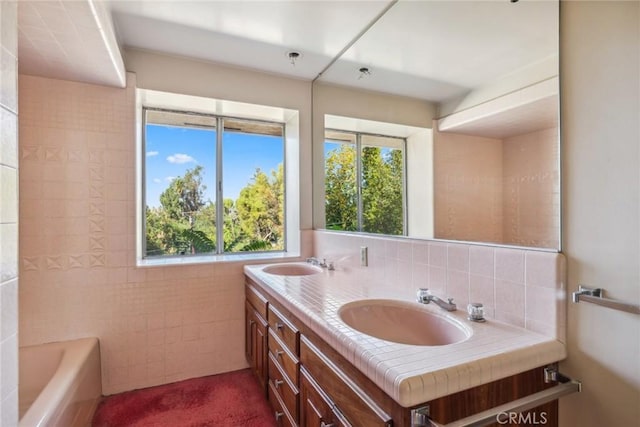 bathroom featuring a bathing tub, decorative backsplash, vanity, and tile walls