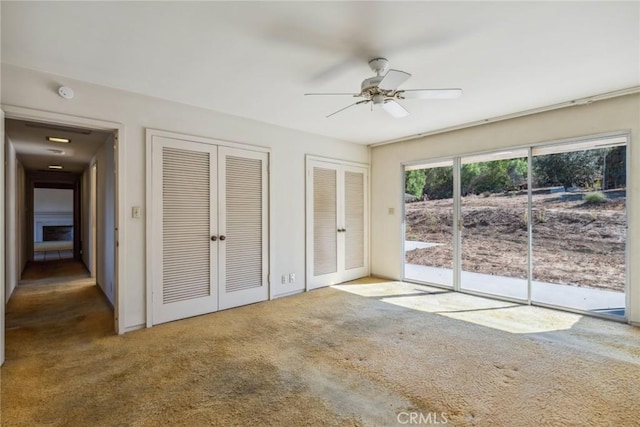 unfurnished bedroom featuring access to exterior, carpet, two closets, and ceiling fan