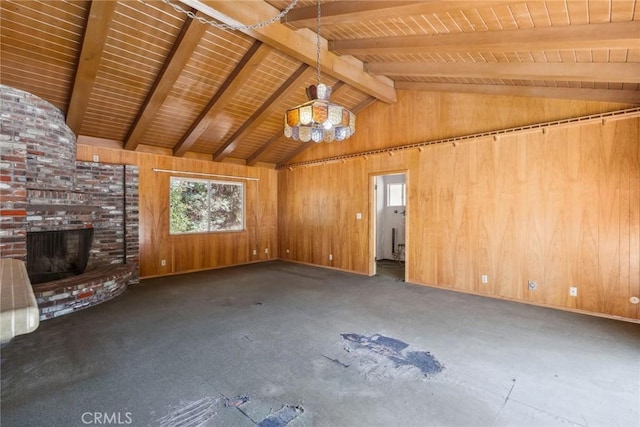 unfurnished living room featuring beam ceiling, a brick fireplace, and wooden walls