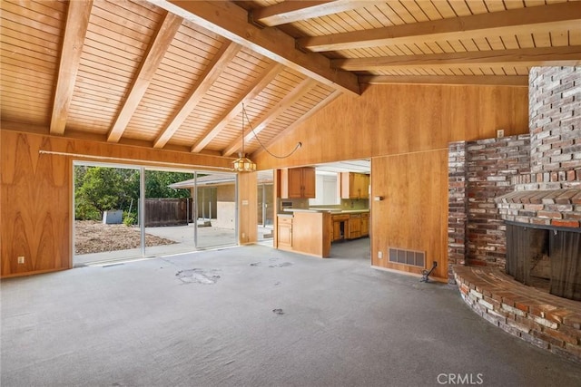 unfurnished living room featuring beam ceiling, wood walls, a fireplace, and high vaulted ceiling