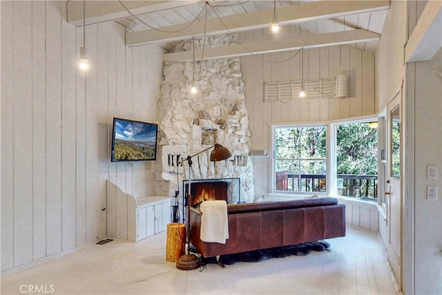 living room with beamed ceiling, high vaulted ceiling, a stone fireplace, and wooden walls