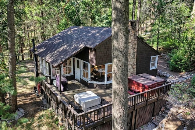 back of property featuring a hot tub and a deck