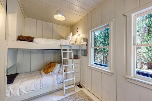 bedroom featuring multiple windows, wooden ceiling, and wood walls