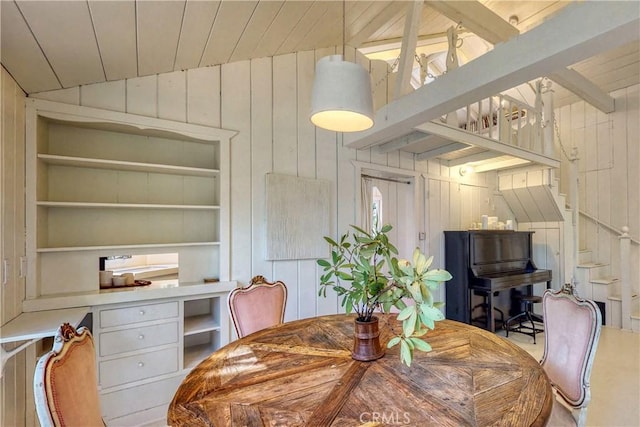 dining area with a wealth of natural light, wood ceiling, built in shelves, lofted ceiling with beams, and wood walls