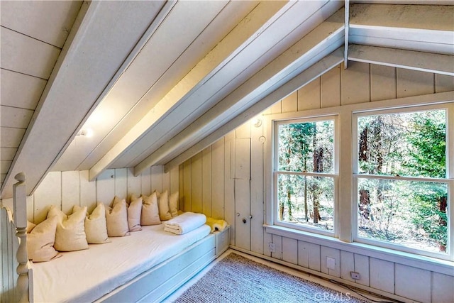 interior space with lofted ceiling with beams, plenty of natural light, and wooden walls