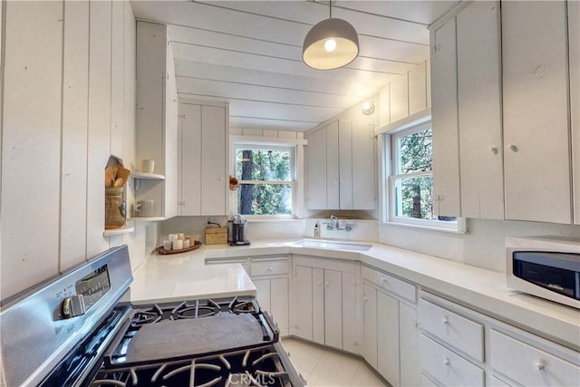 kitchen featuring white cabinets, range, hanging light fixtures, and a wealth of natural light