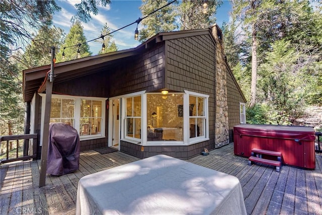 wooden deck with area for grilling and a hot tub