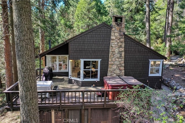 back of property featuring a wooden deck and a hot tub