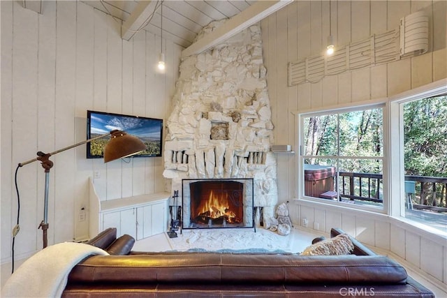 living room with high vaulted ceiling, a stone fireplace, and wooden walls