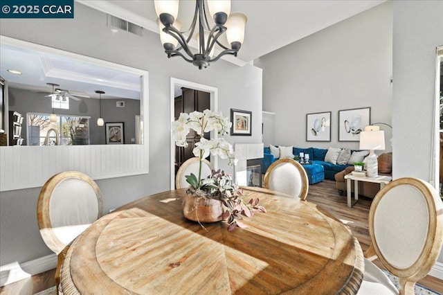 dining space with hardwood / wood-style flooring, ceiling fan with notable chandelier, and crown molding