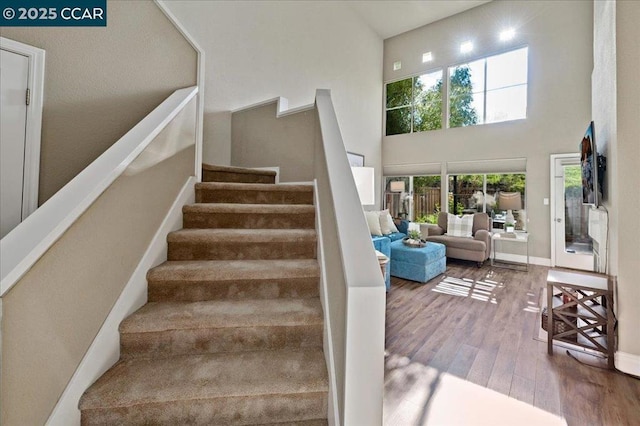 stairs with wood-type flooring and a towering ceiling