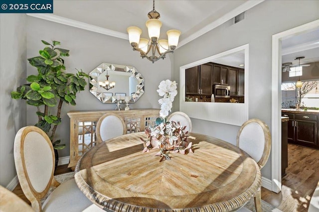 dining area with wood-type flooring, a chandelier, and ornamental molding