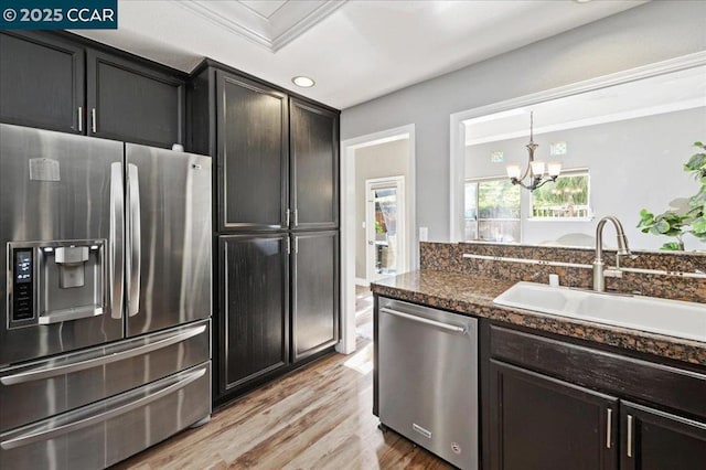 kitchen with light hardwood / wood-style flooring, dark stone countertops, appliances with stainless steel finishes, sink, and ornamental molding