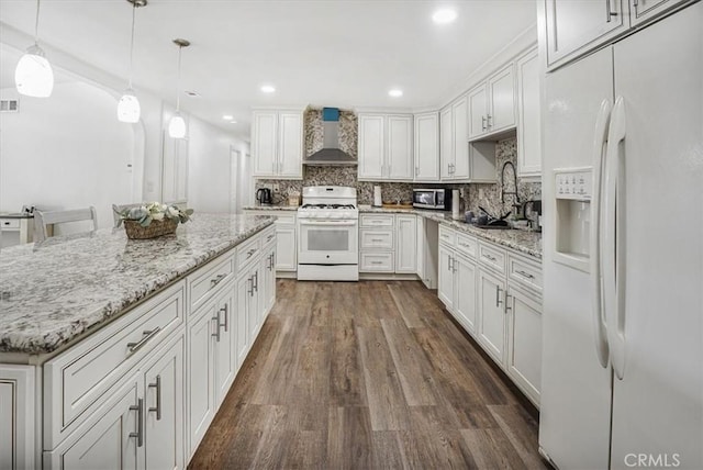 kitchen with wall chimney range hood, decorative backsplash, white appliances, white cabinetry, and hanging light fixtures