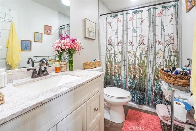 bathroom with toilet, a shower with curtain, wood-type flooring, and vanity