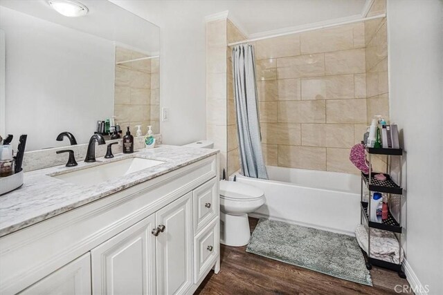 full bathroom with hardwood / wood-style flooring, toilet, vanity, and shower / bathtub combination with curtain