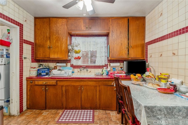 kitchen featuring tasteful backsplash, ceiling fan, sink, and tile walls