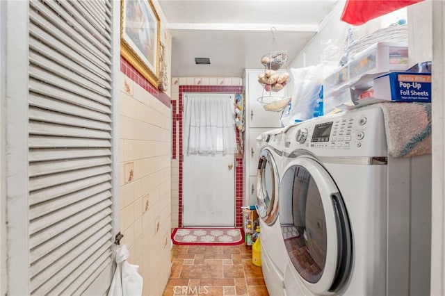 laundry area with washing machine and dryer and tile walls