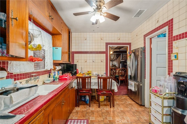 kitchen featuring tile counters, stainless steel fridge, tile walls, and ceiling fan