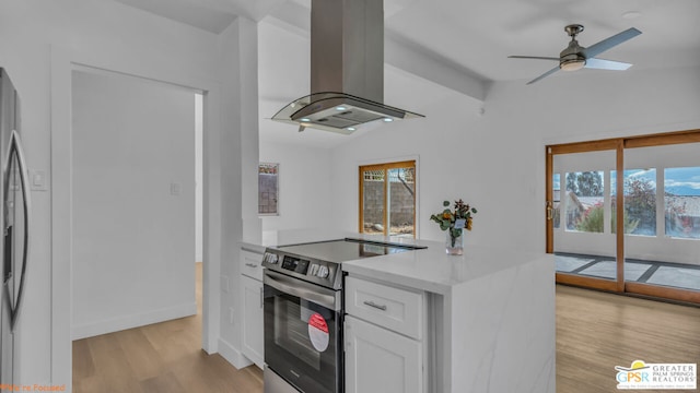 kitchen featuring stainless steel electric stove, white cabinets, ceiling fan, light wood-type flooring, and island range hood