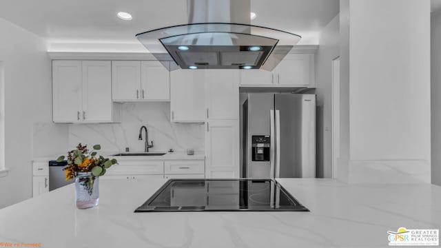 kitchen with white cabinetry, sink, stainless steel fridge with ice dispenser, light stone counters, and black electric cooktop