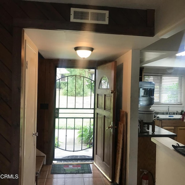 doorway to outside with dark tile patterned floors and sink