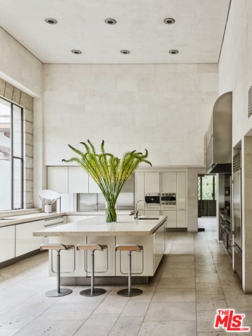 kitchen with sink, white cabinets, a kitchen bar, and an island with sink