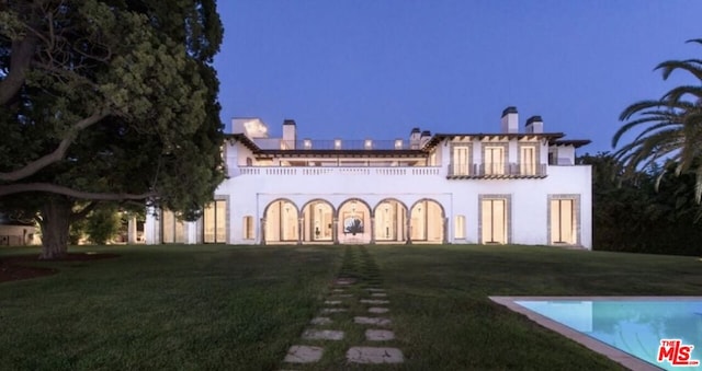 rear view of property featuring a lawn and a balcony