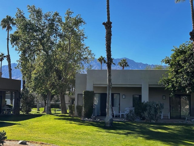 back of property with a mountain view and a lawn