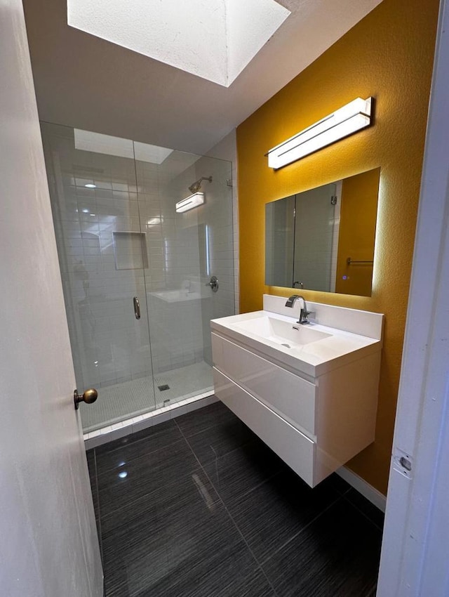 bathroom featuring a skylight, tile patterned flooring, vanity, and an enclosed shower