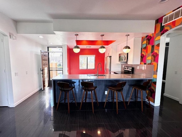 kitchen featuring white cabinetry, stainless steel appliances, hanging light fixtures, kitchen peninsula, and a breakfast bar area