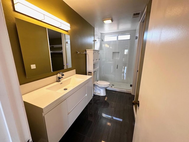 bathroom featuring tile patterned floors, vanity, toilet, and a shower with door