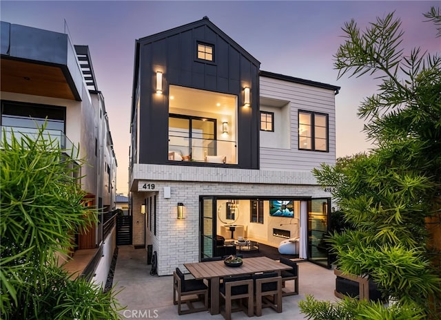 back house at dusk with a balcony and a patio