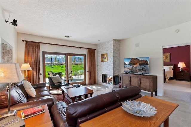 living room featuring a textured ceiling and a stone fireplace