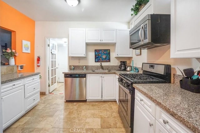 kitchen with white cabinets, appliances with stainless steel finishes, stone countertops, and sink