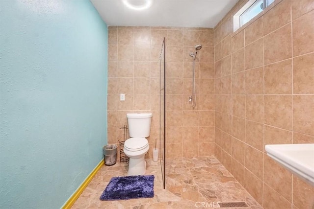 bathroom with a tile shower and toilet