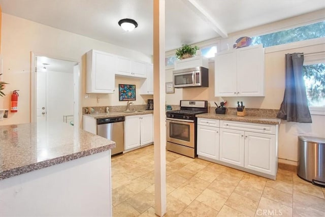 kitchen with beam ceiling, white cabinetry, sink, and appliances with stainless steel finishes