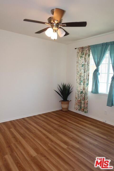 spare room featuring ceiling fan and dark wood-type flooring