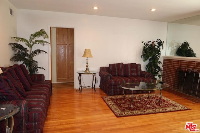 living room featuring wood-type flooring and a brick fireplace