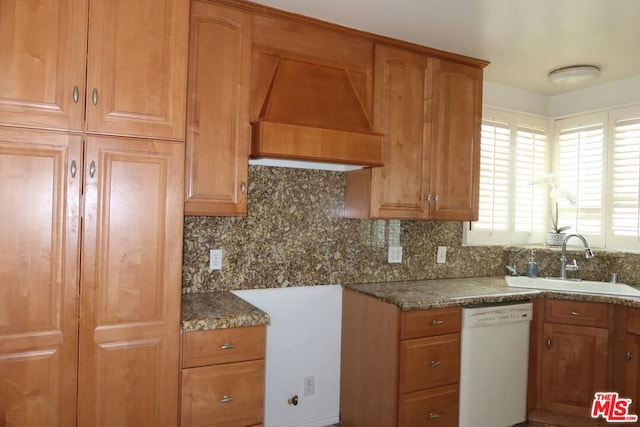 kitchen with backsplash, custom exhaust hood, sink, dark stone countertops, and dishwasher